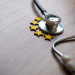 Closeup image of stethoscope and five stars on wooden table.