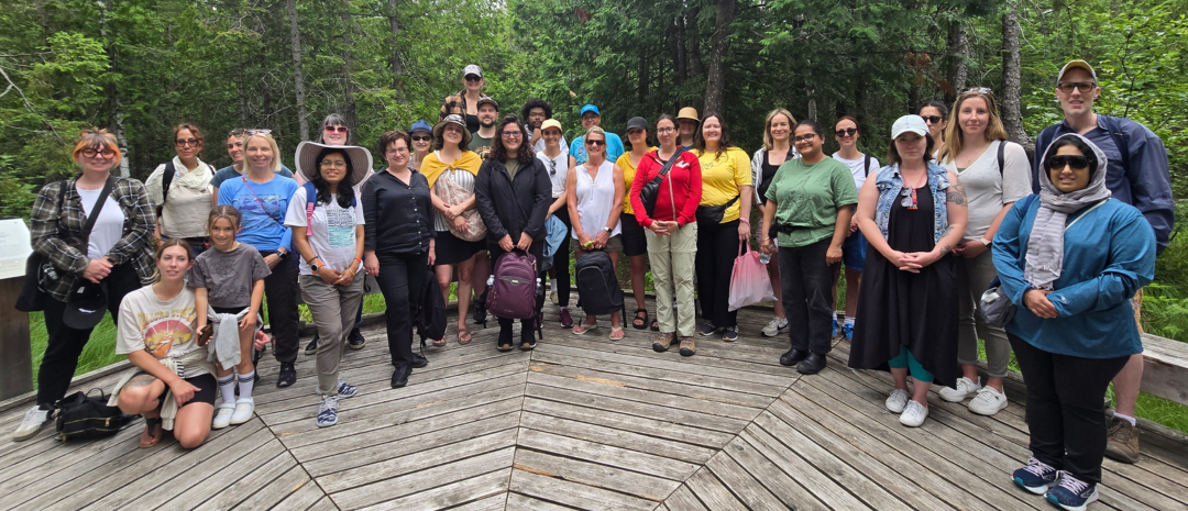 A group of Summer Institute participants posing for a photo on a wooden platform in the forest.