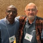 Two people posing for a photo with their arms on each other's back.