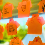 Orange origami shirts with handwritten messages such as 'Every Child Matters' displayed on a window, commemorating the National Day for Truth and Reconciliation.
