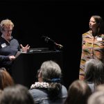 Dr. Julie Chamberlain (left) and Dr. Christine Mayor stand at the podium in front of community members, university students and project partners presenting their study findings.