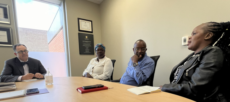 Four people meet at a boardroom table.