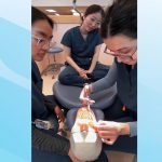 A student practices a procedure on a dentistry mannequin in a dental clinic. Two students watch.