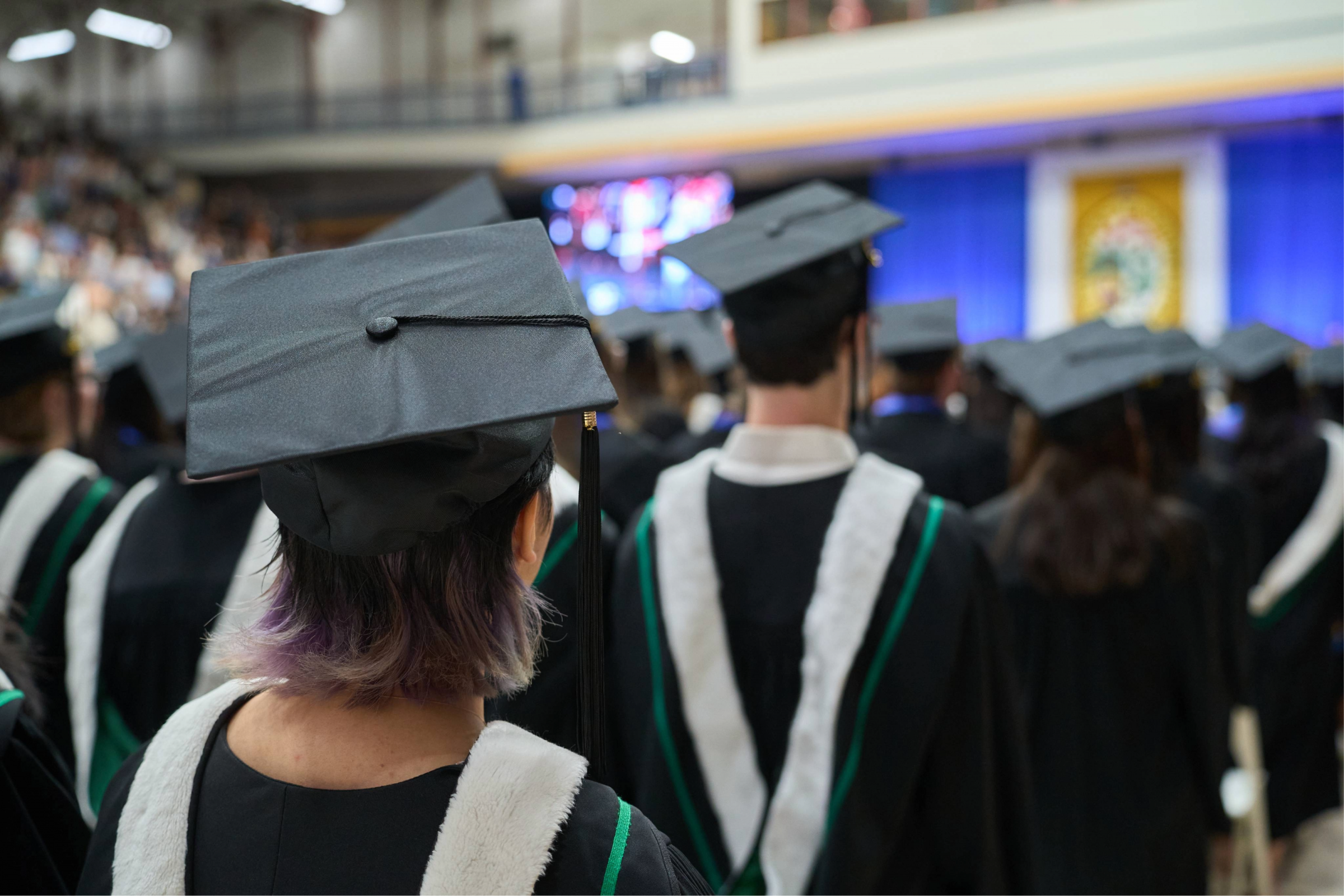 UM students in caps and gowns file into the Convocation space.