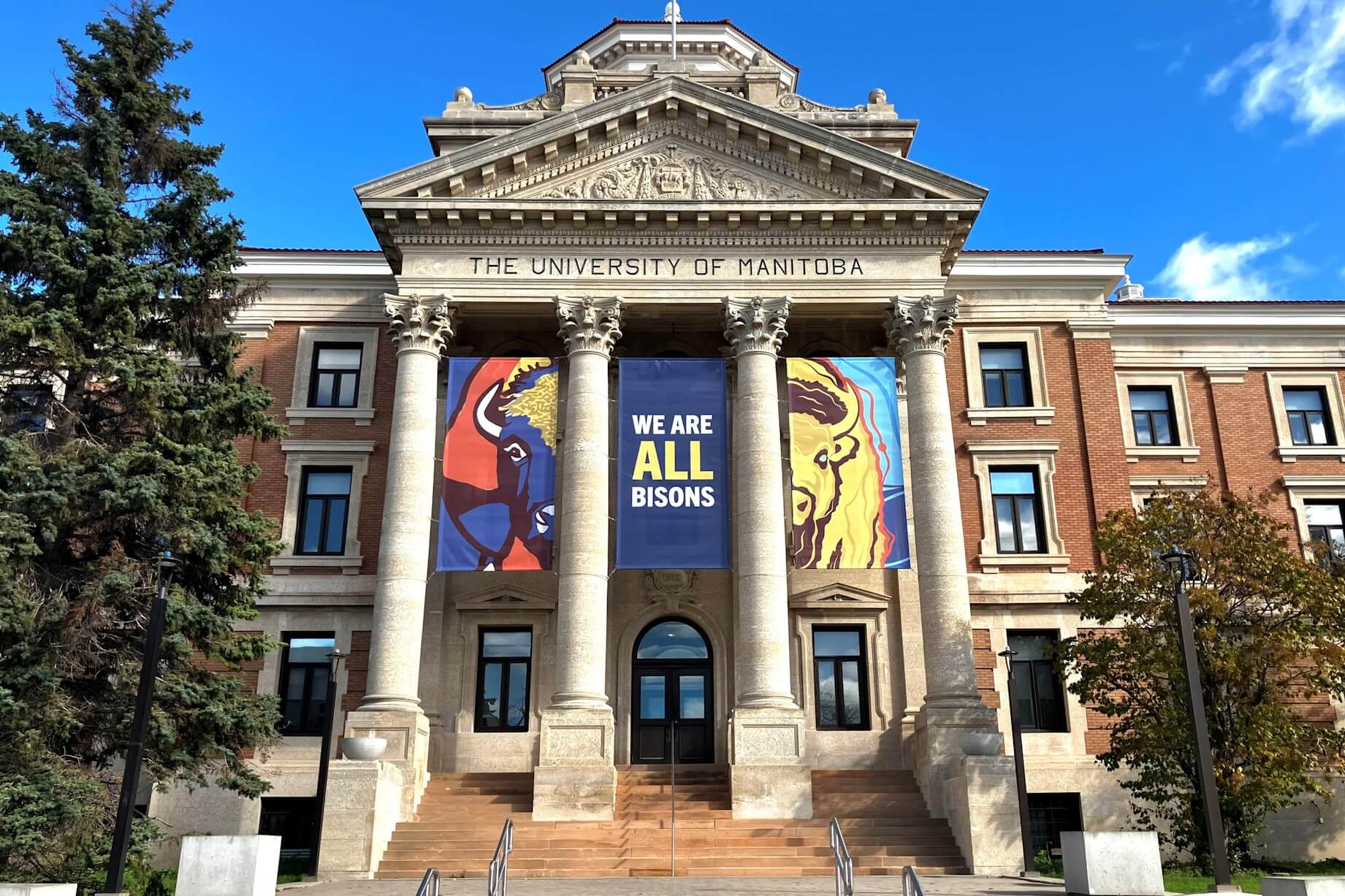 Three banners hang from the Administration Building, two with bison faces and the third with text stating "We are all bisons.: