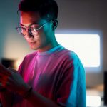 Young man looking at his tablet in a darkly lit room.