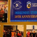Bulletin board display featuring photos and a blue poster reading “University of Manitoba Indigenous Studies 50th Anniversary.”