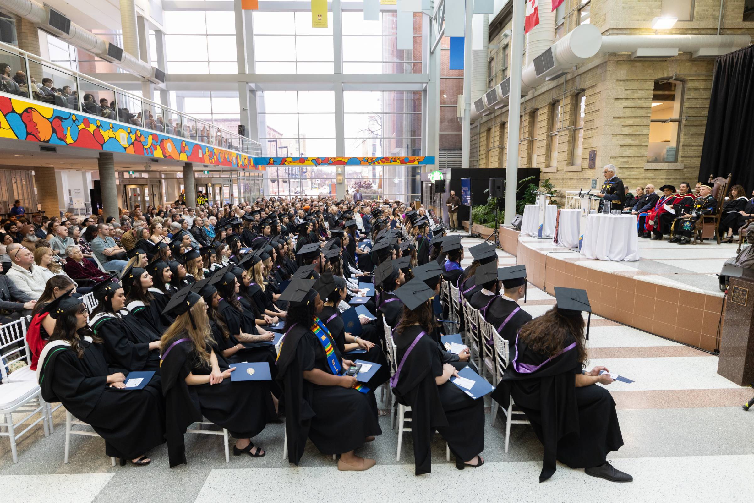 Graduands seated for convocation at Bannatyne campus. University of Manitoba president Michael Benarroch addresses them from the stage.