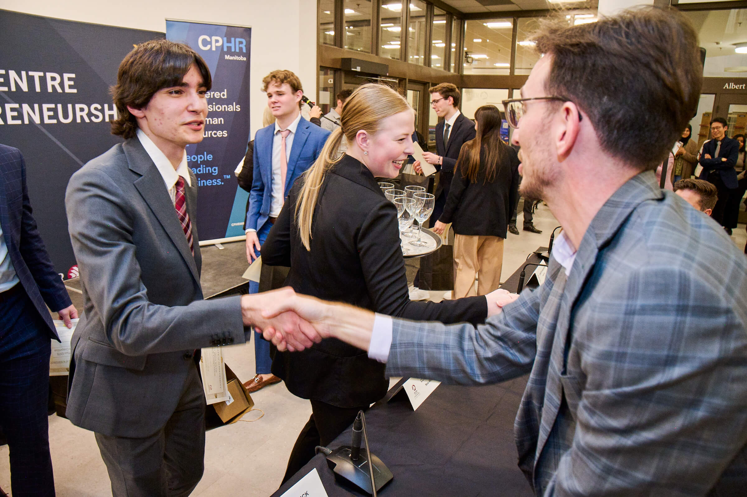 The winning student in the CPHR pitch competition shakes the hand of judge Matt Schaubroeck, a Manitoba entrepreneur and founder of Leverage Point Consulting. // Photo by Tony Nardella
