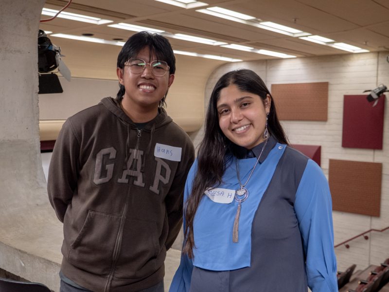 Two students smile at the camera.
