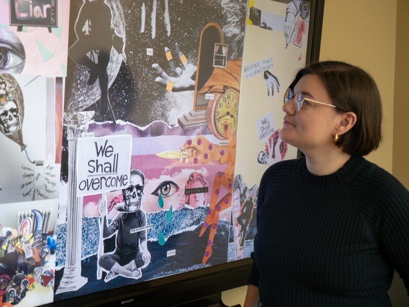 Jen Sebring looks at a digital display showing a collage of participant-created artwork.