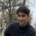 Photo of Riley Parker in a cable-knit sweater in front of trees outdoors