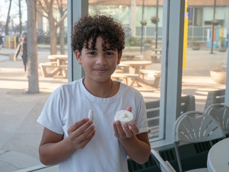 Grade 9 student smiling at the camera while holding a finger mould and a tooth model used for a filling exercise.