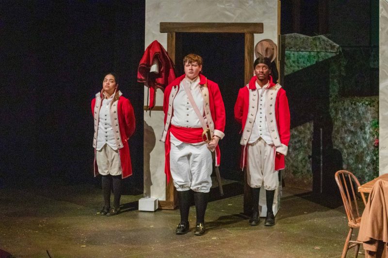 Student actors performing on stage wearing 19th century costumes.