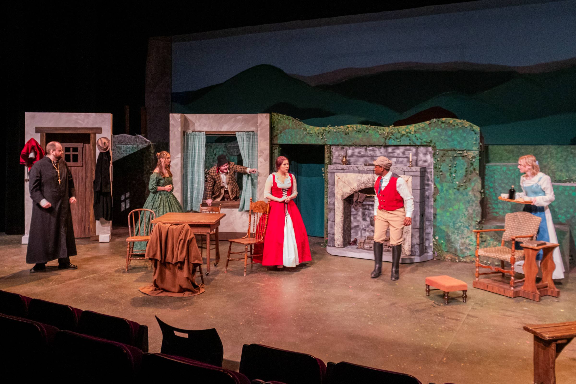 Six student actors performing on stage wearing period costumes from the 19th century.
