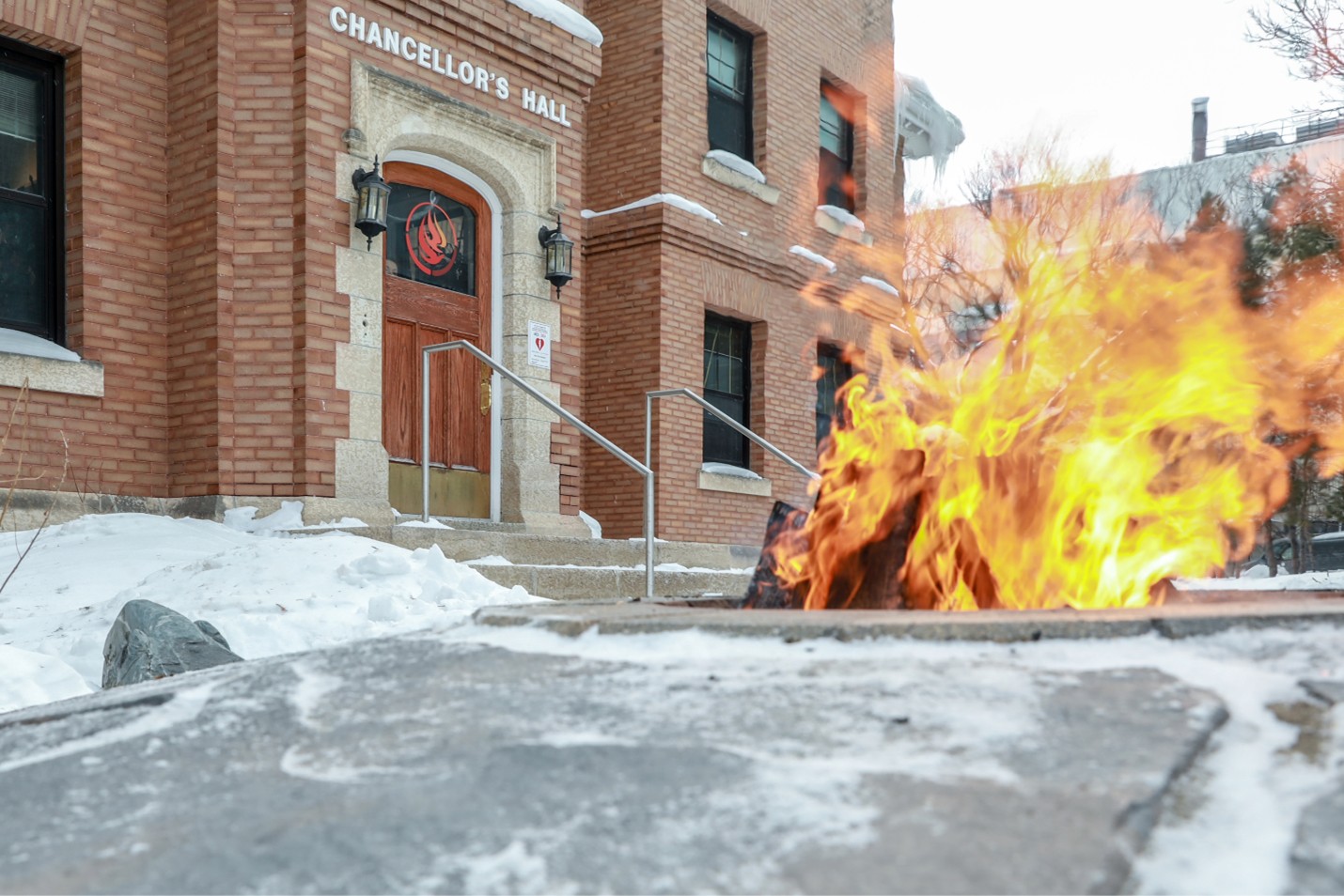 fire burns in fire pit outside of brick building in the winter