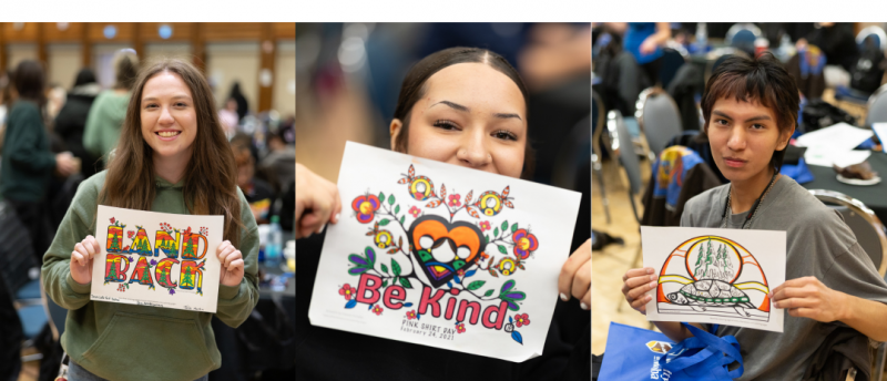 Three students at a campus gathering hold up their completed colouring pages featuring Indigenous-inspired artwork with messages such as ‘Land Back,’ ‘Be Kind,’ and a turtle with trees.