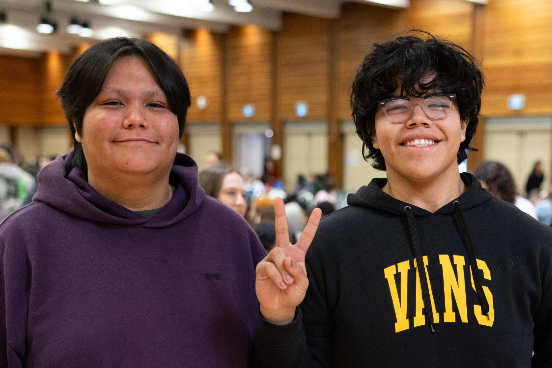 Two attendees smile for the camera at the event, one holding up a peace sign.