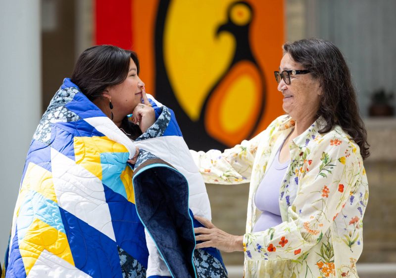 Two women proudly looking at one another as they open arms for a hug