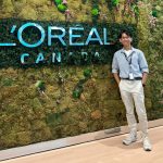 Jared Salvador smiling in front of a vertical garden wall featuring the L’Oréal Canada logo.