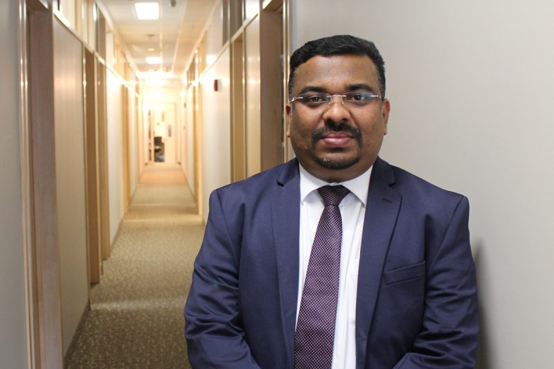 Jithan Sreedharan stands in a hallway at the College of Rehabilitation Sciences.