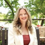 Dr. Marnie Kramer sits on an outdoor bench in summer.