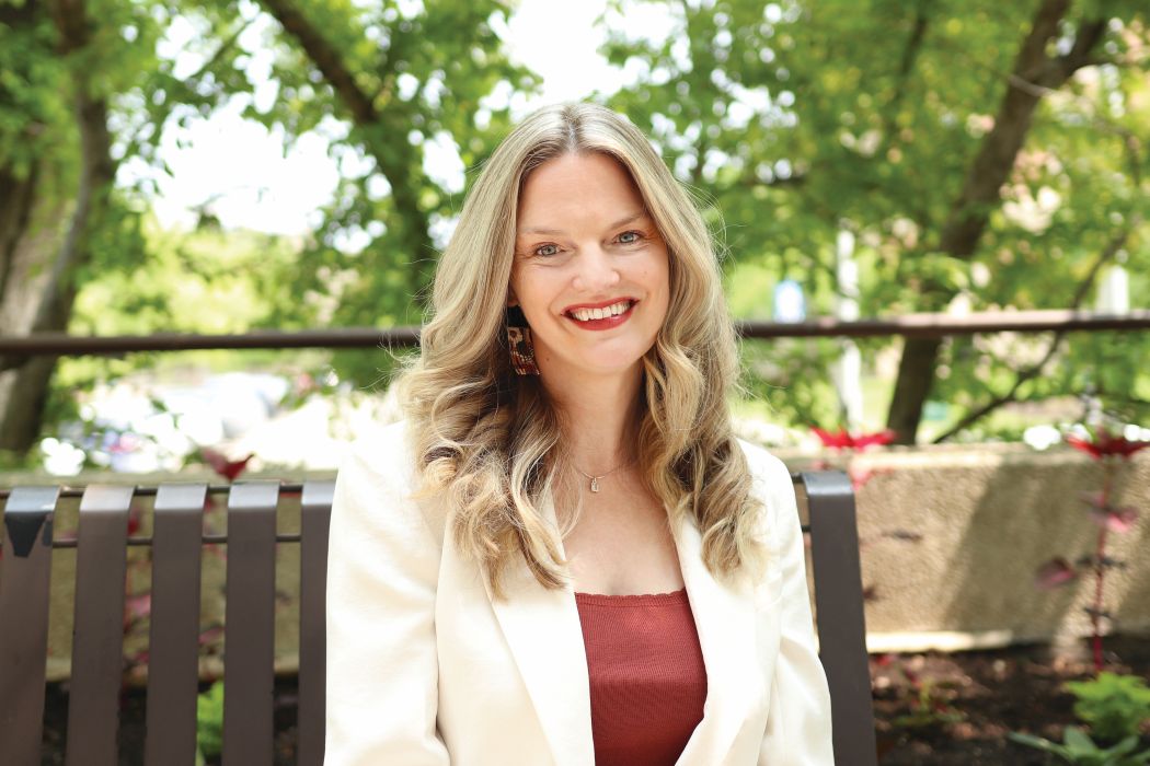 Dr. Marnie Kramer sits on an outdoor bench in summer.