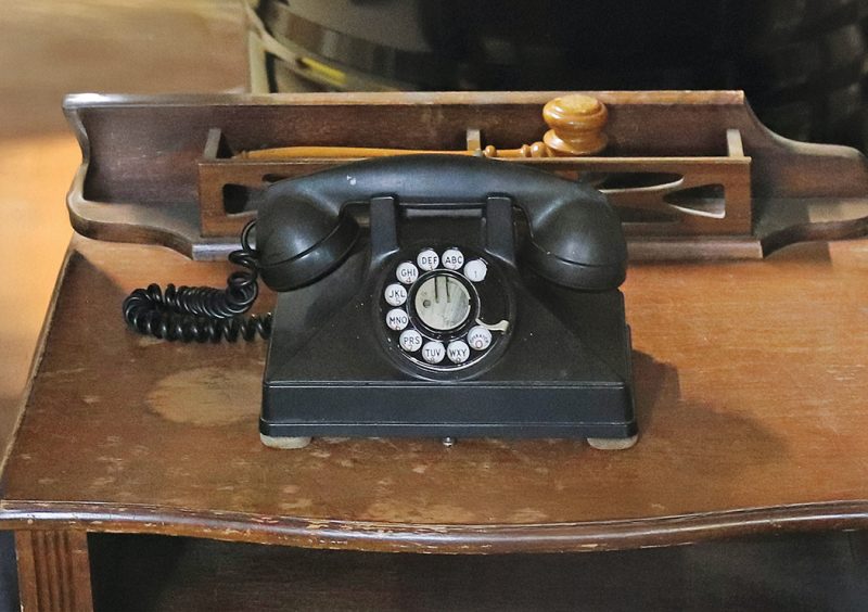 An old rotary phone on a wooden desk.