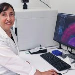 Person smiling at the camera while working on a computer.