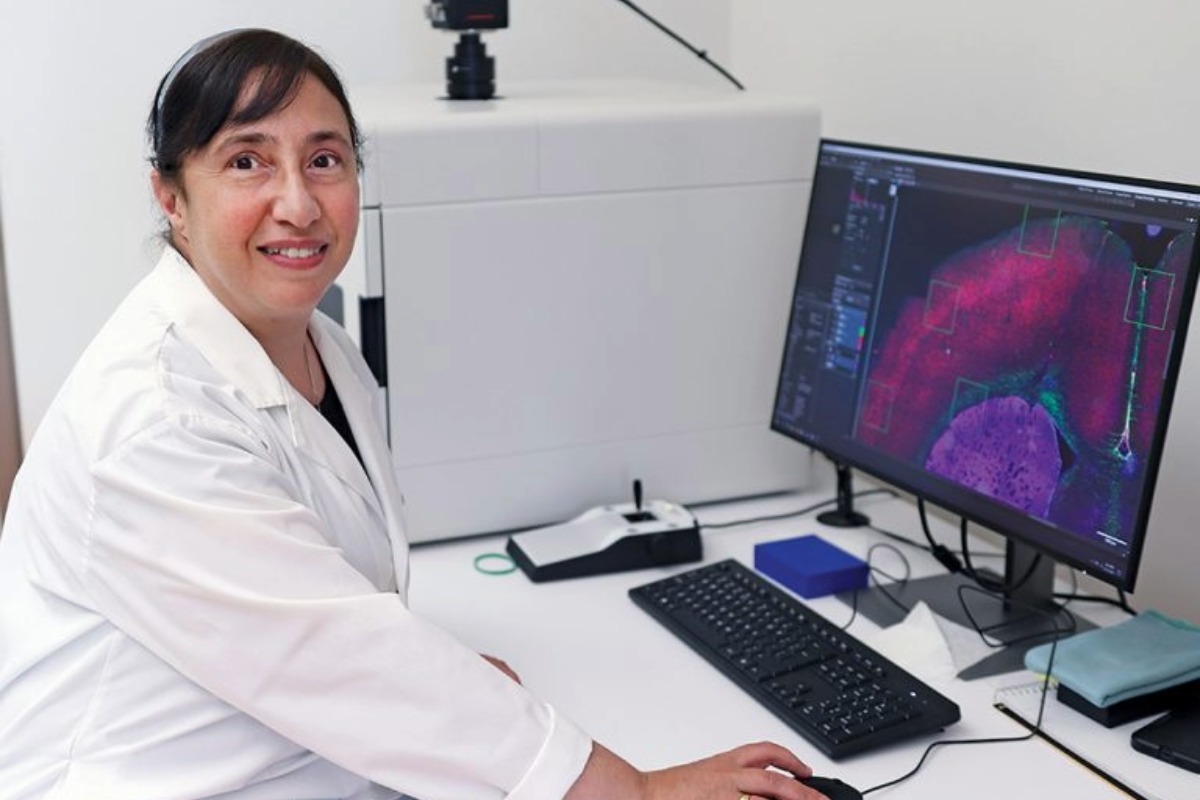 Person smiling at the camera while working on a computer.