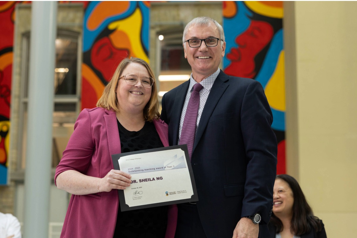 Two people smiling at the camera. Dr. Sheila Ng, on the left, is holding a certificate.