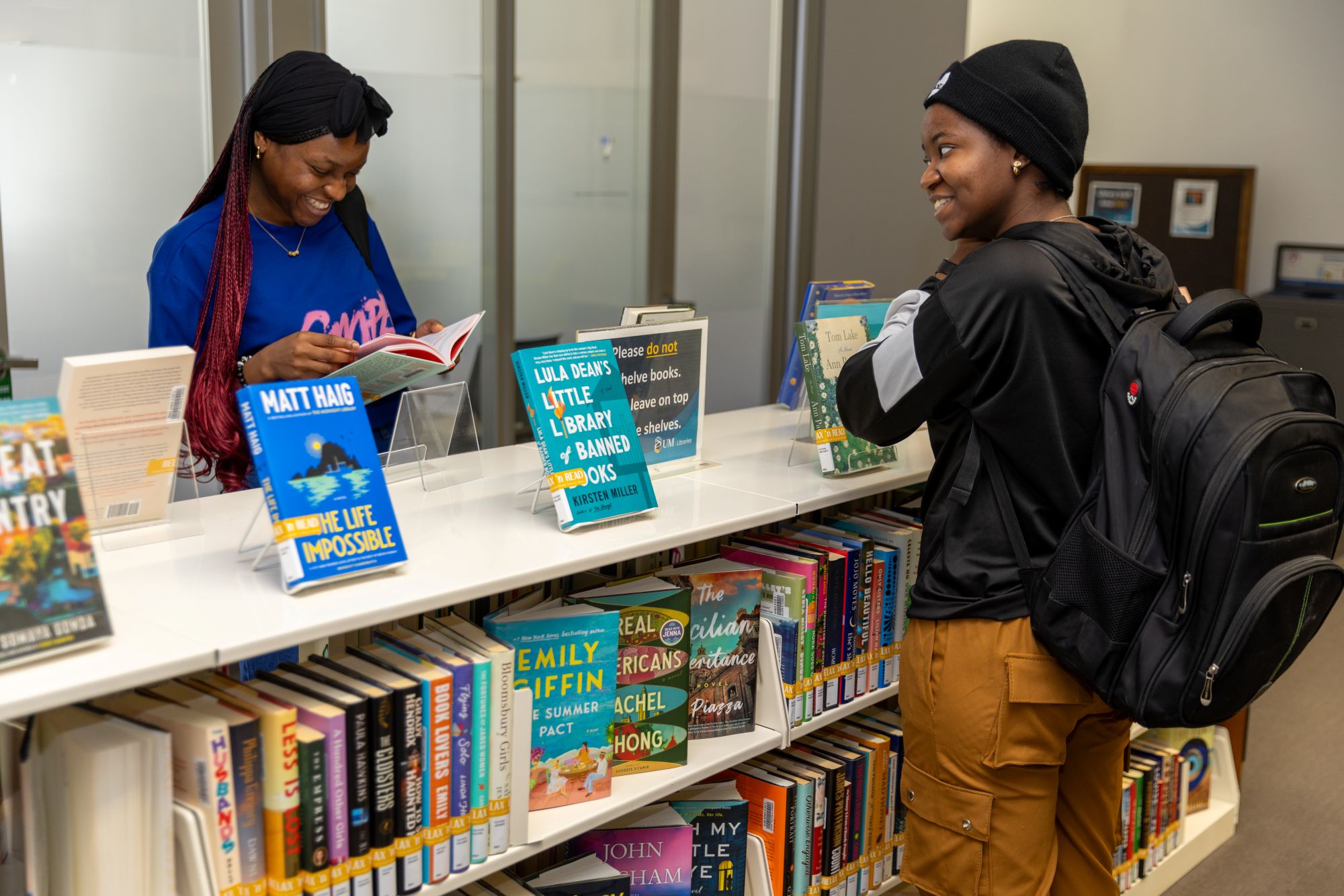 Two students browsing a bookshelf of colourful books