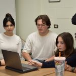 Science student group discussing and referencing from the laptop.