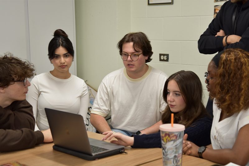 Science student group discussing and referencing from the laptop.