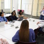 A library staff member teaching a group of students sitting at a table
