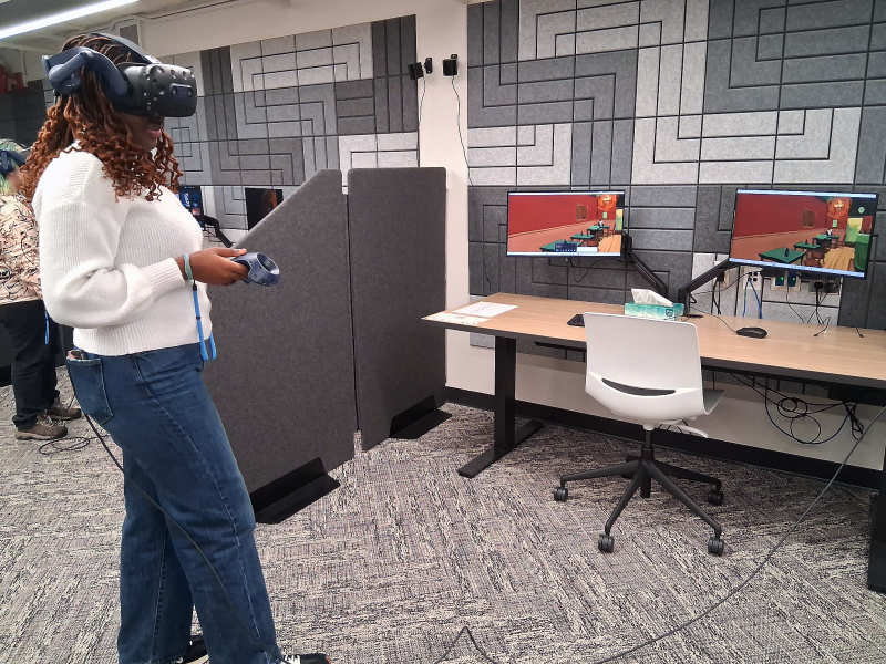 A student using a VR headset with art on computers in front of them