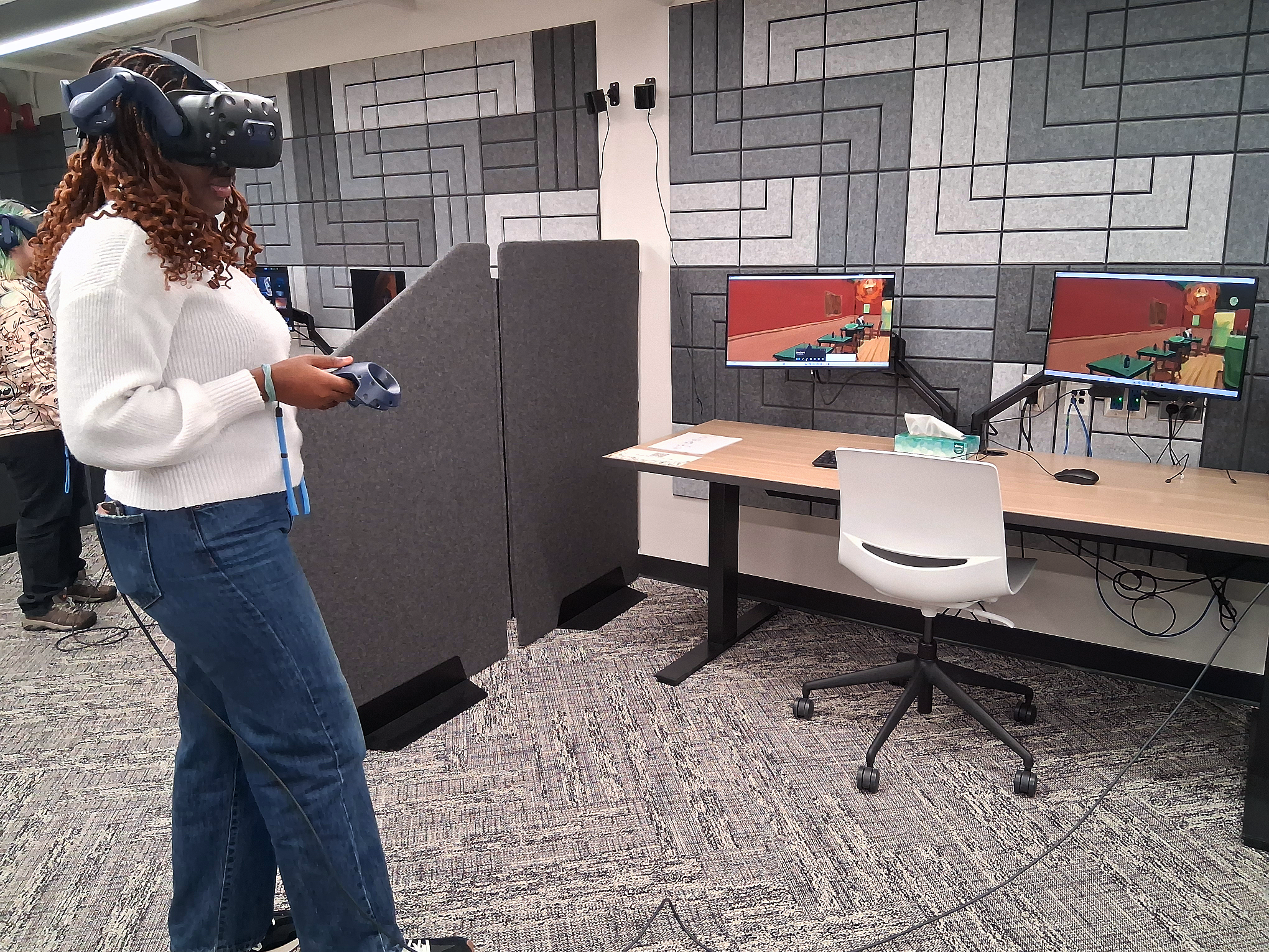A student using a VR headset with art on computers in front of them