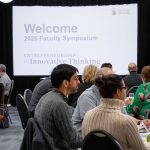 Faculty members sitting at tables at the 2025 Faculty Symposium.