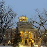 Snow covered UM Admin building from the patio of UMSU University Centre, with snow covered trees in the foreground on the mild and cloudy morning of January 5, 2026 - Zachary LeClerc