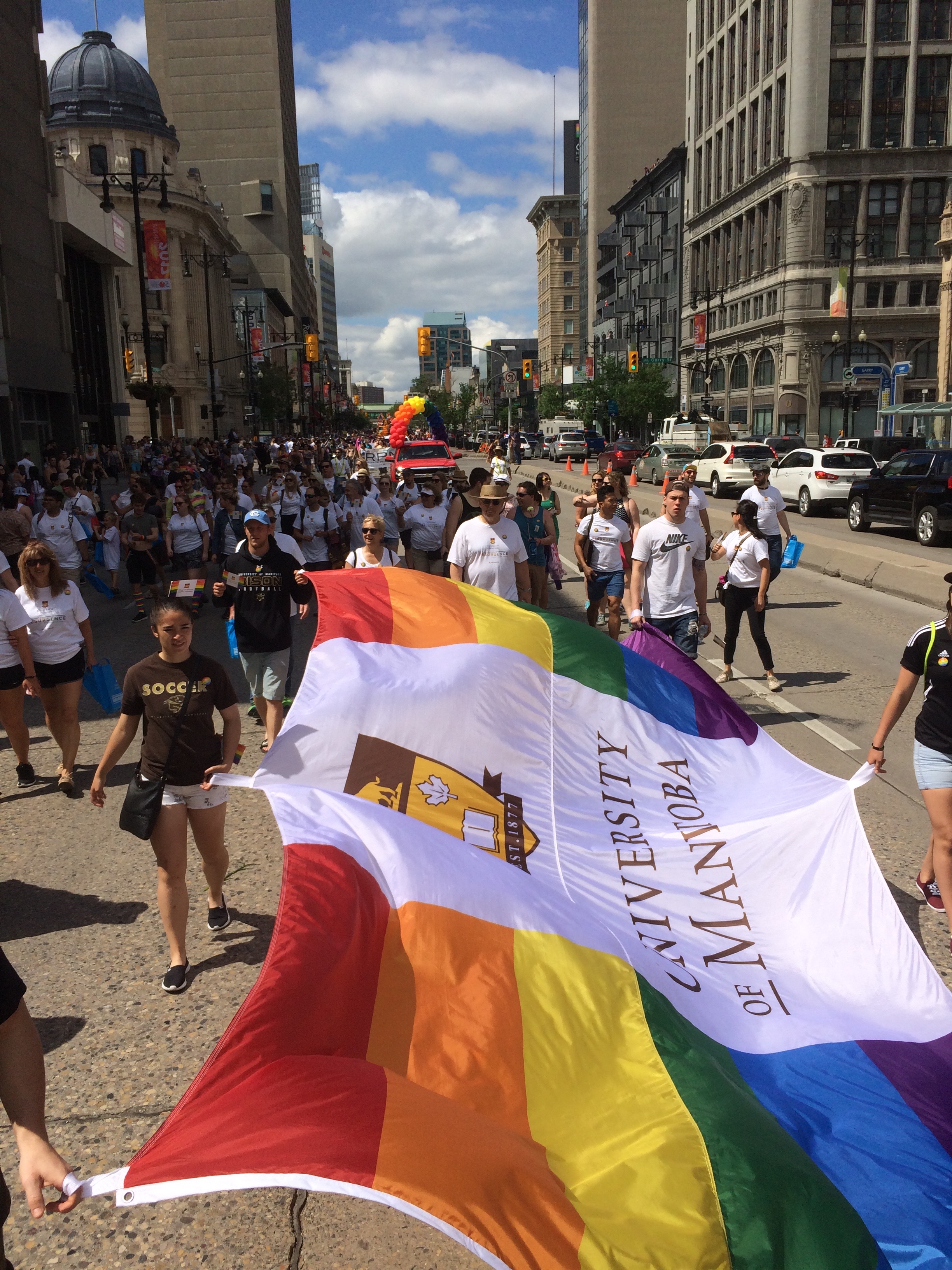 Bison athletes march down Portage Avenue with the U of M Pride flag on June 4.
