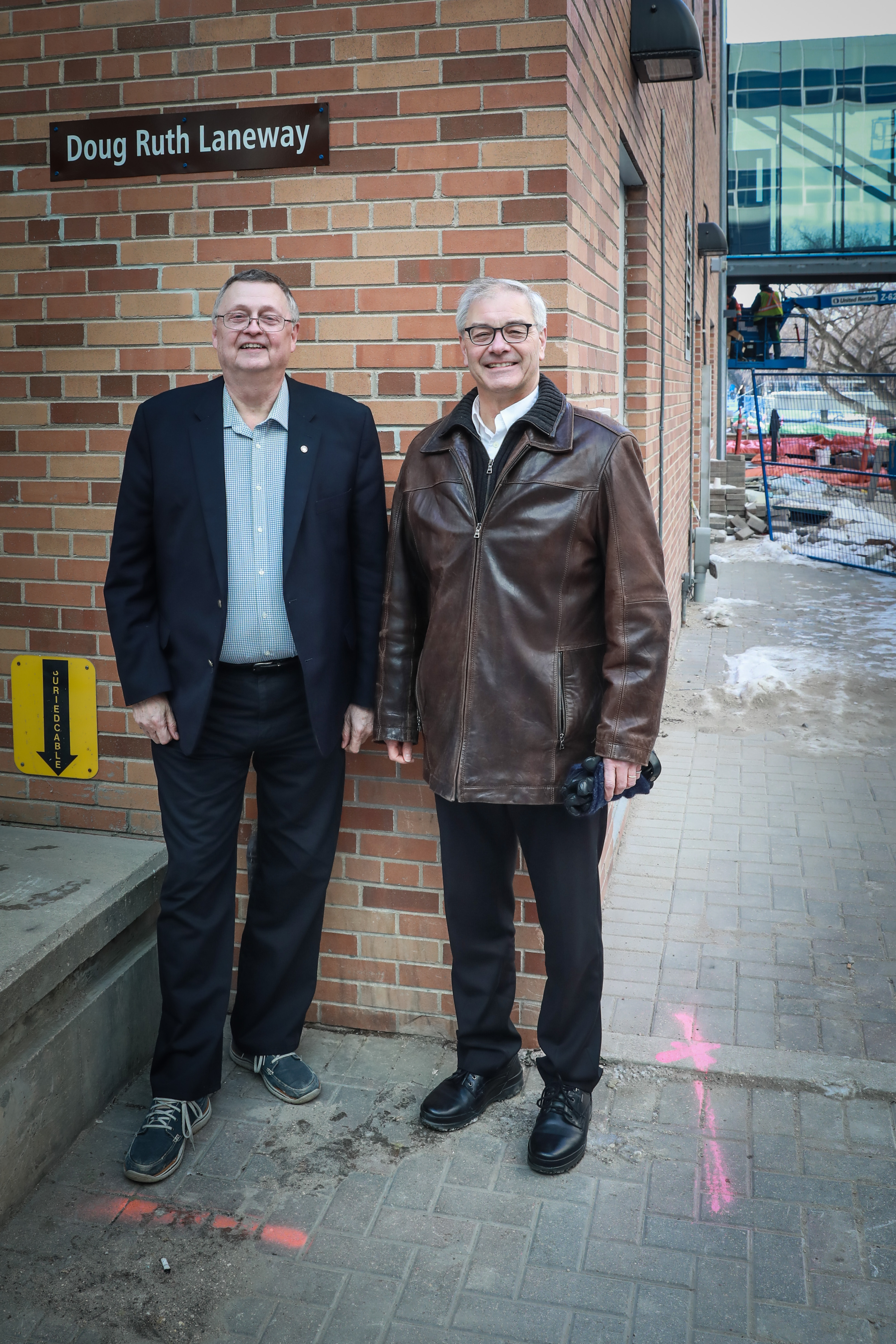 Alt: Doug Ruth with Jonathan Beddoes. Both are standing in front of sign reading "Doug Ruth Laneway", smiling and posing for the camera.