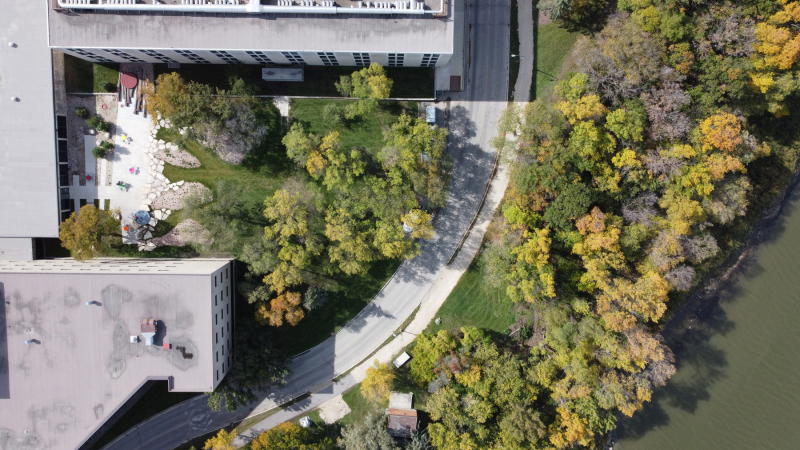 An aerial view shows a building complex with a courtyard, surrounded by greenery, contrasting structured and organic elements.