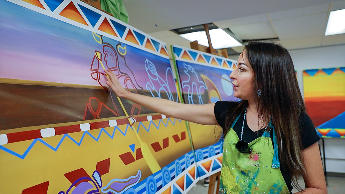 Kristin Flattery—Ozhaawashkwaa Mashkode-Bizhiki paints the mural.